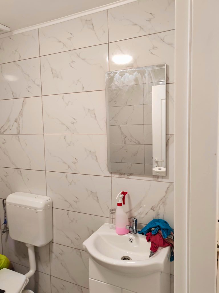 Baie renovată, cu faianță cu aspect de marmură și lavoar