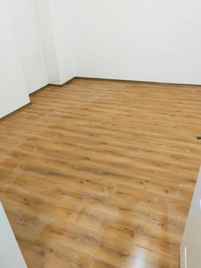 Parchet laminat în nuanță de stejar, într-o cameră zugrăvită în alb